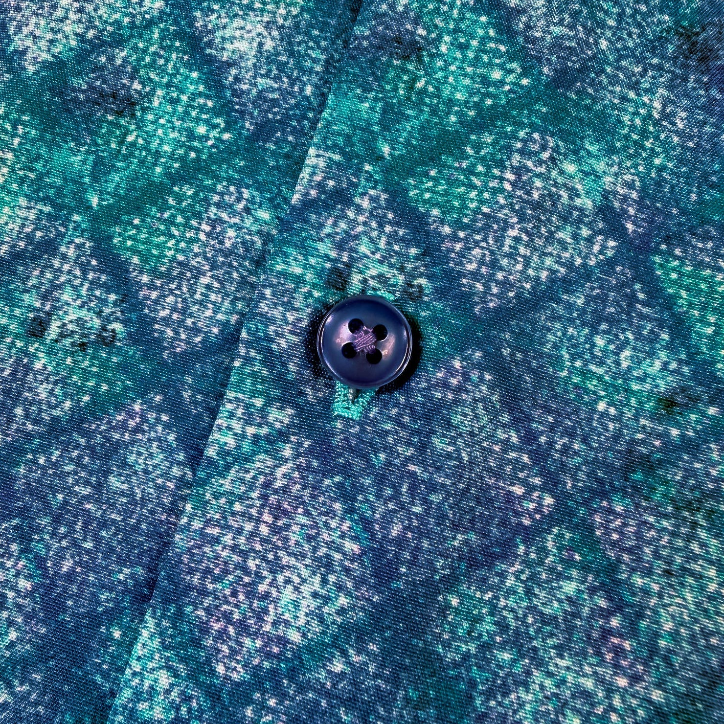 Close-up of a blue and green patterned fabric with a button.