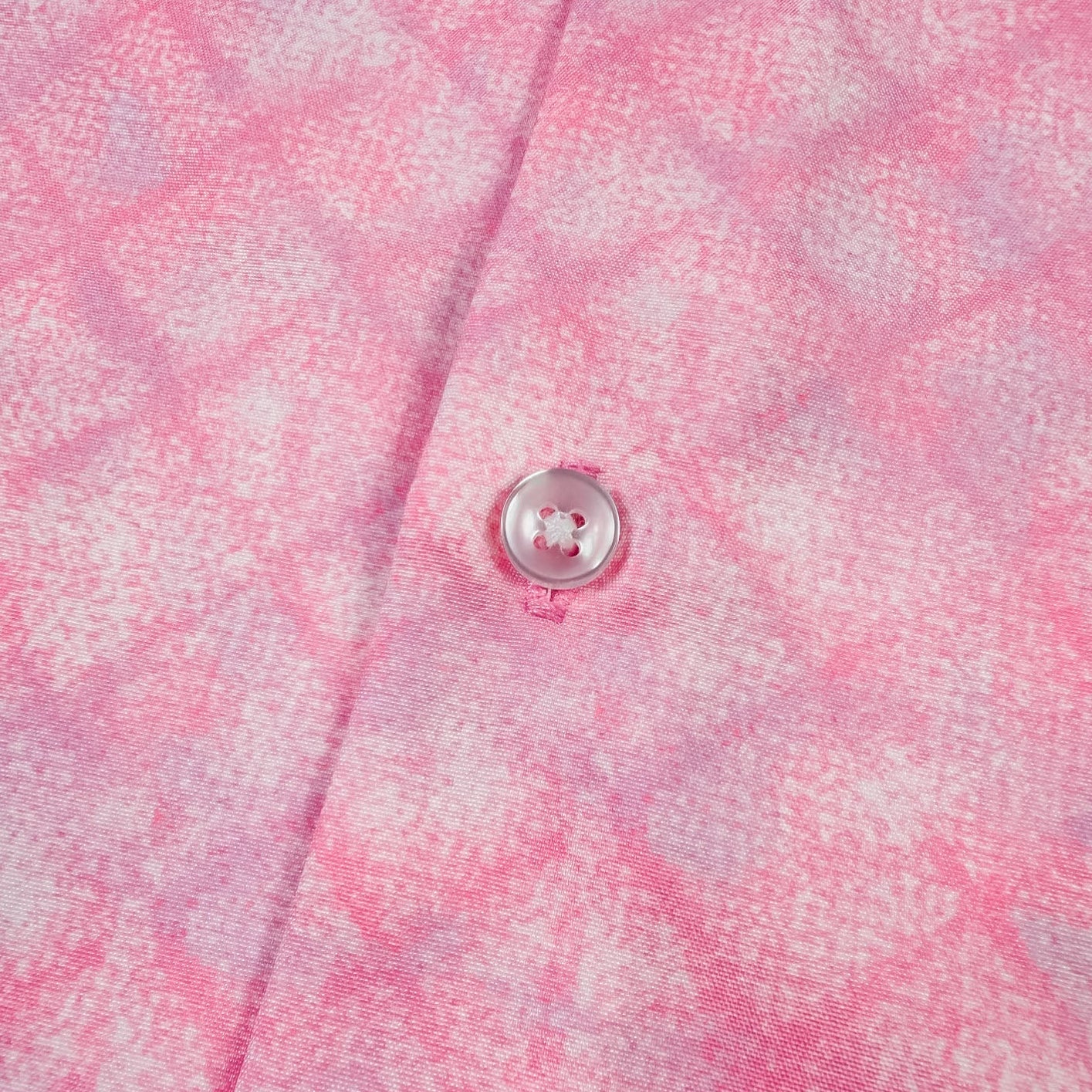 Close-up of a pink checkered shirt with a button.