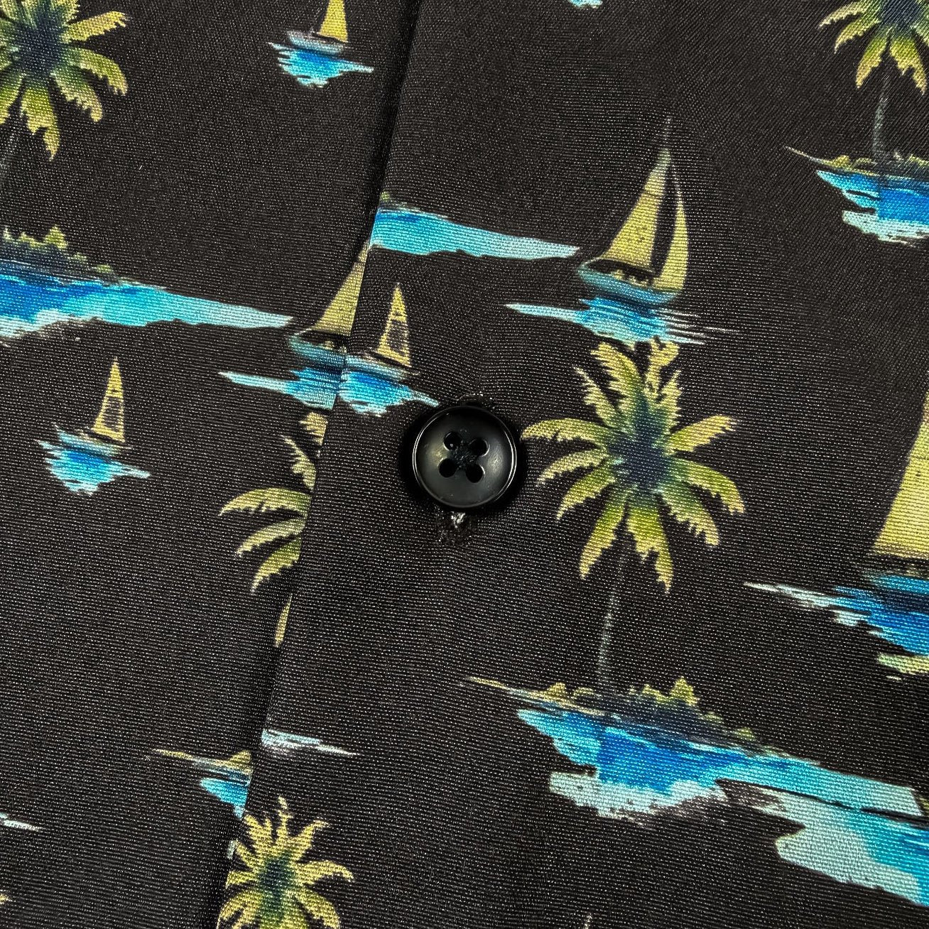 Black shirt with tropical pattern featuring palm trees and sailboats.