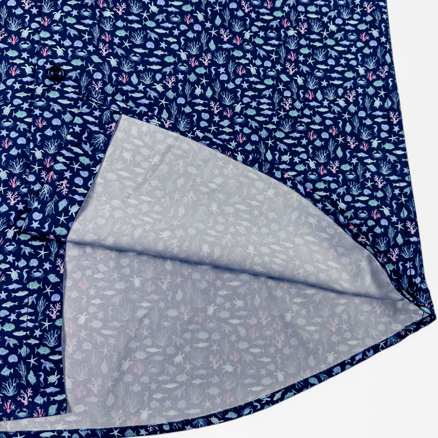 Folded shirt with blue floral pattern on one side and gray polka dot pattern on the other, on a white background.