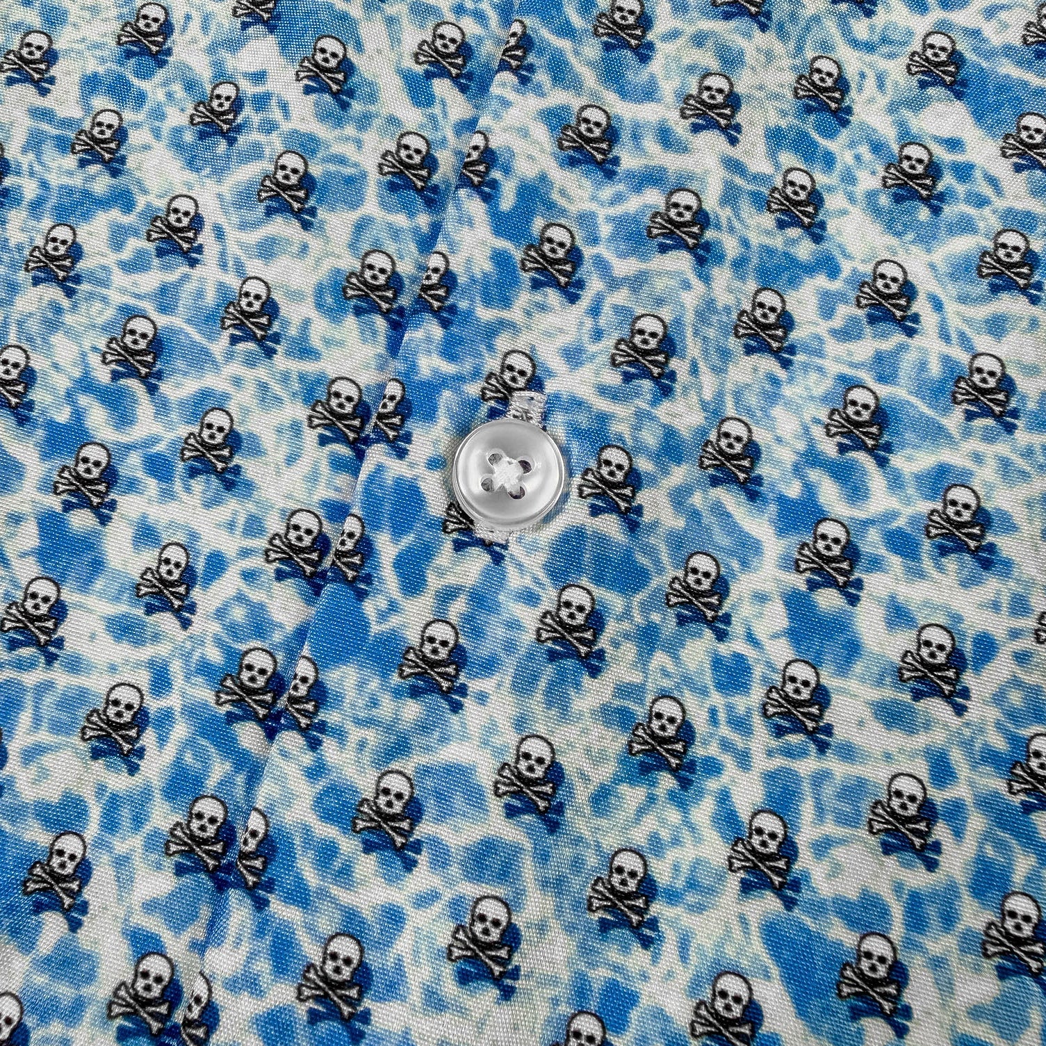 Blue and white patterned fabric with small skull and crossbones design