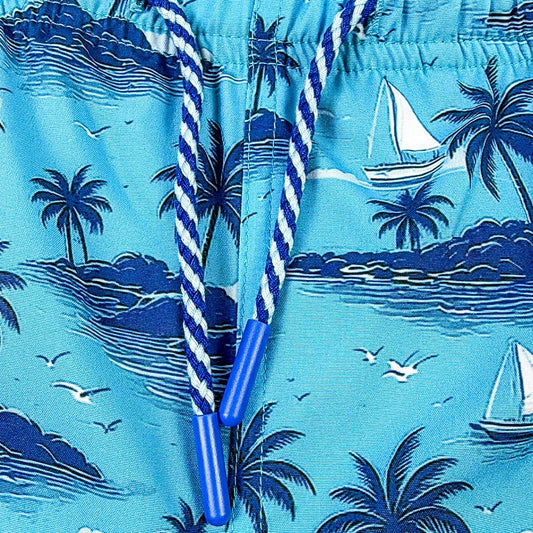 Blue swim shorts with tropical island pattern and sailboats.