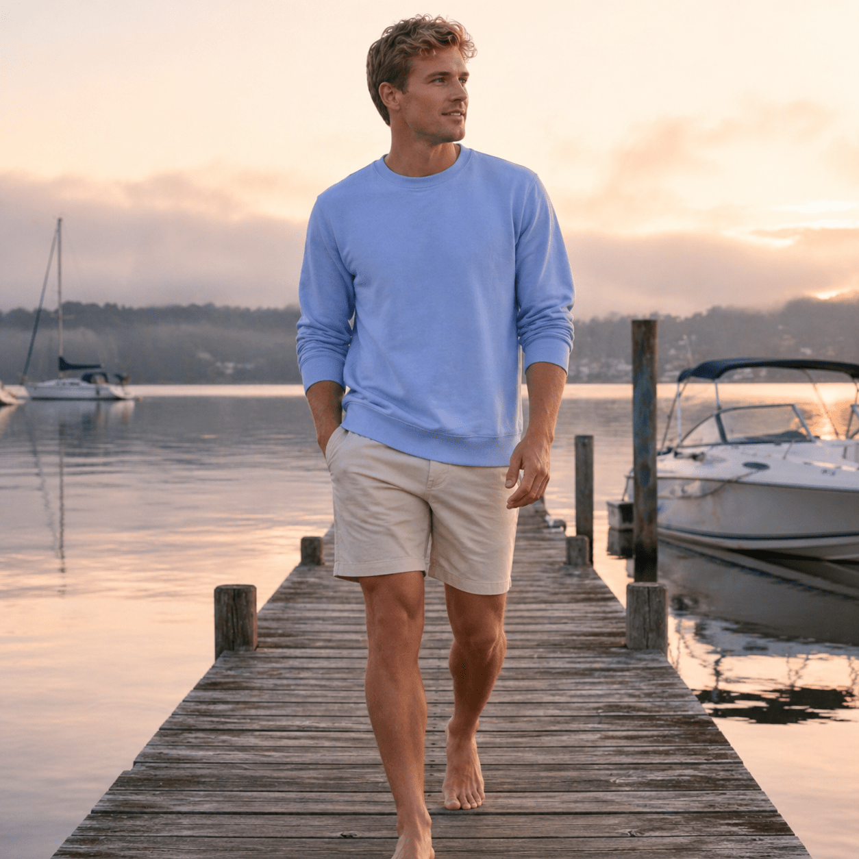 Man walking on a dock by a lake with boats in the background