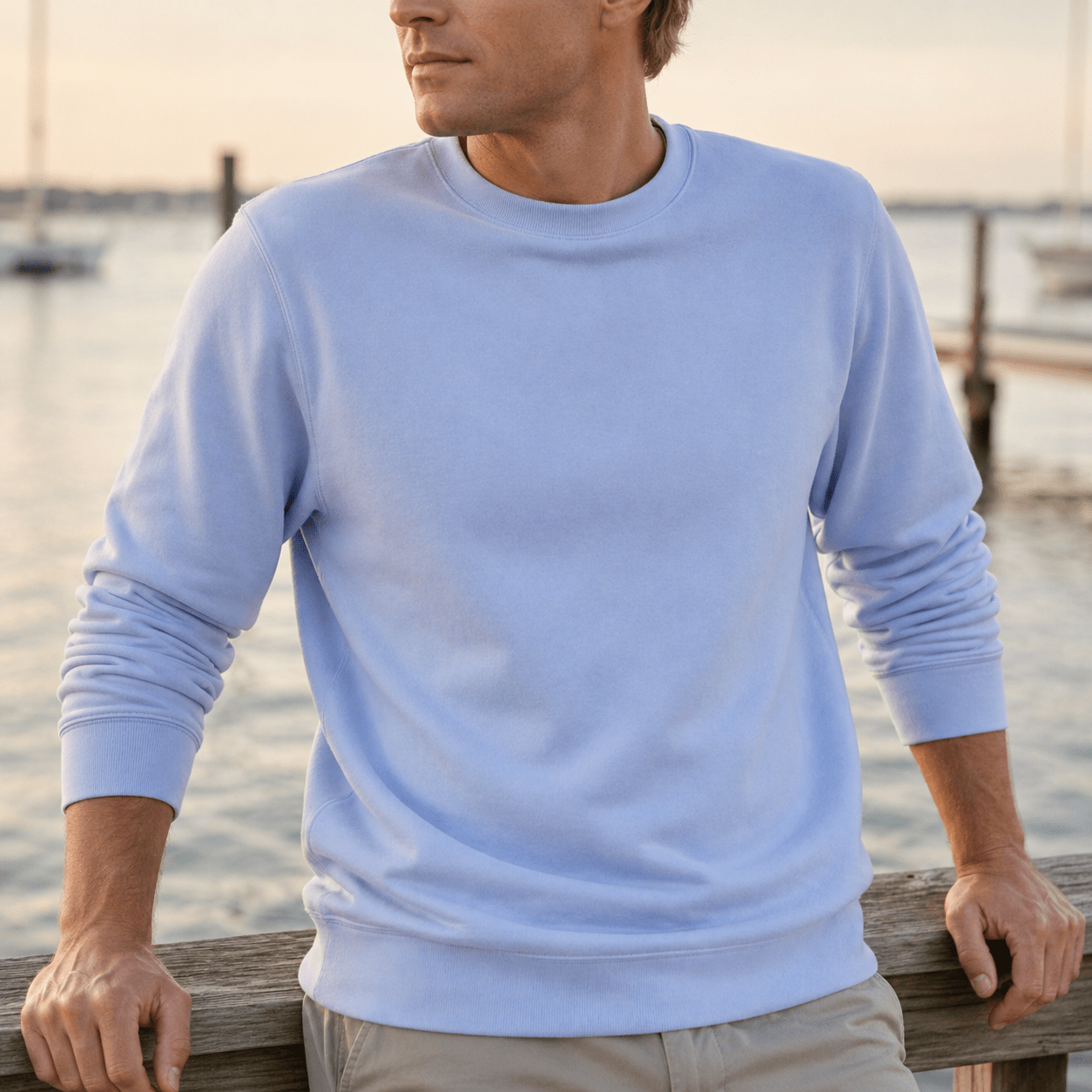 Man wearing a light blue sweatshirt by a waterfront
