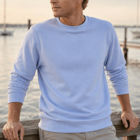 Man wearing a light blue sweatshirt by a waterfront
