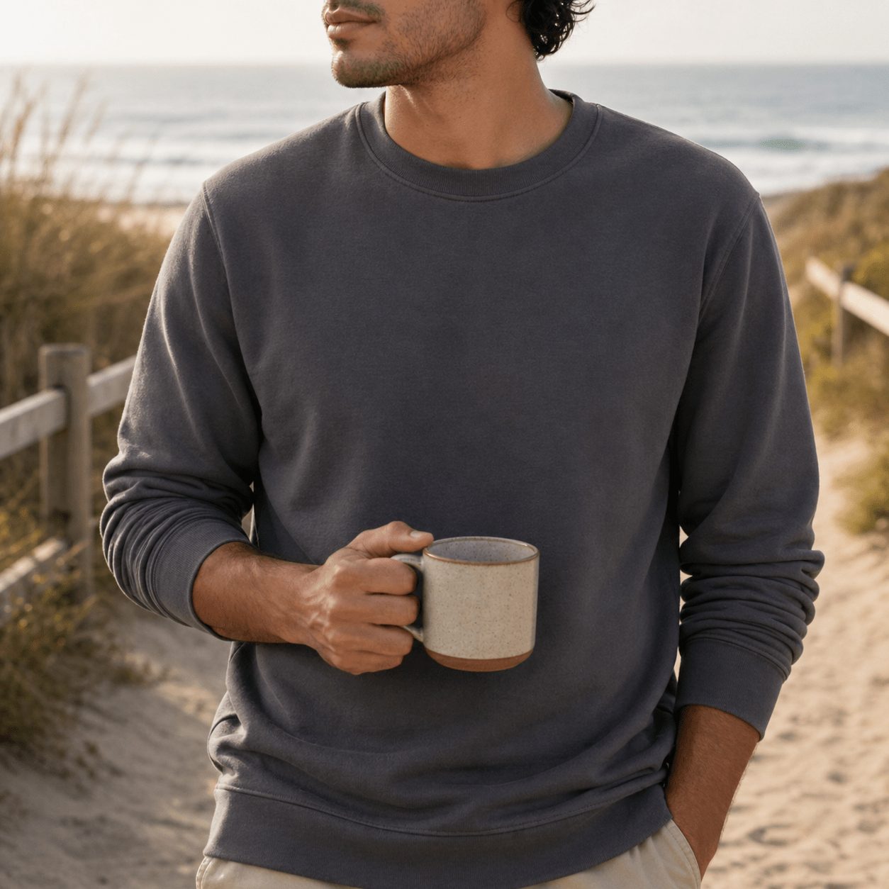 Man holding a mug on a beach with ocean view