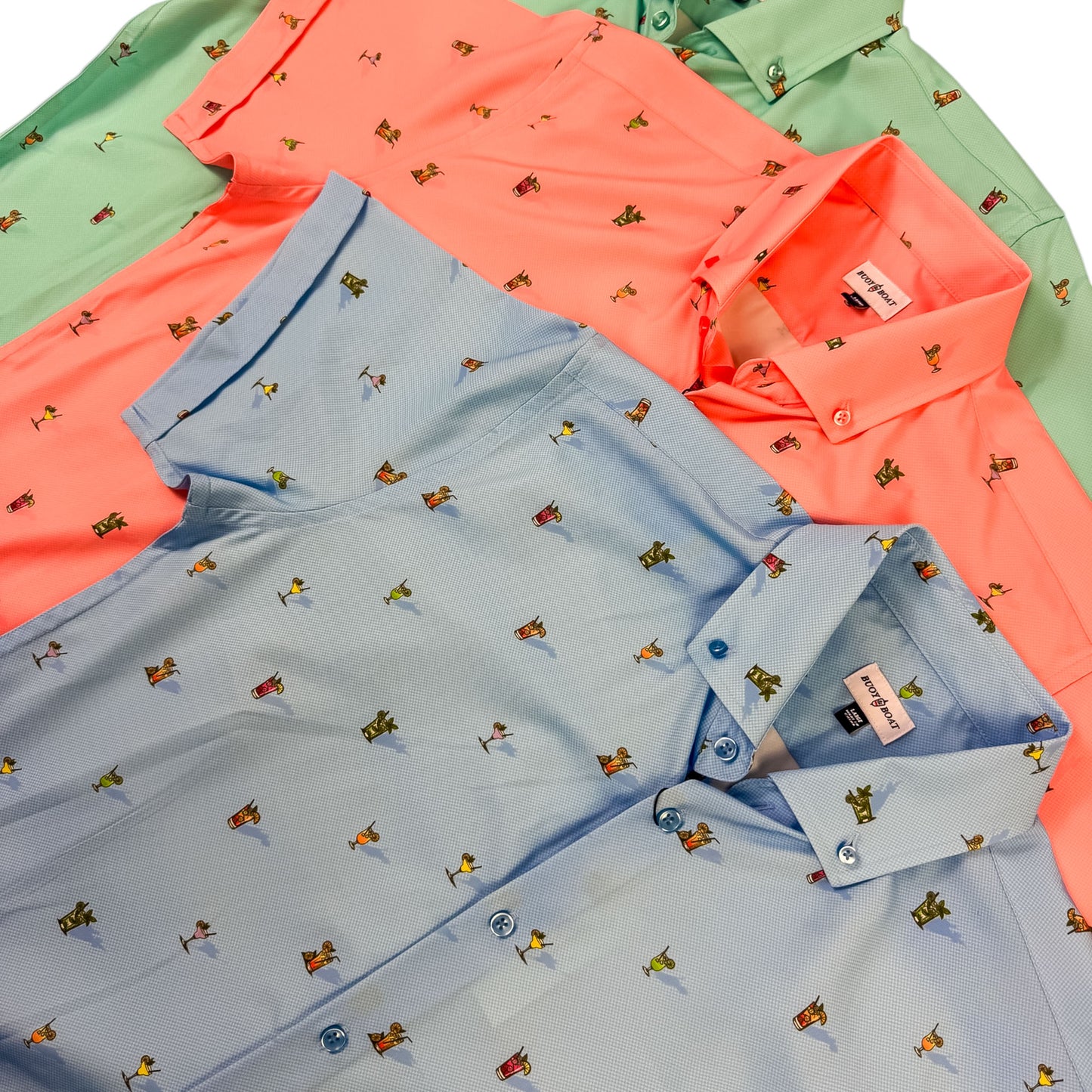 Three folded shirts in green, orange, and blue with small patterns on a white background