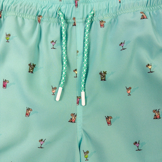 Teal shorts with a pattern of small figures and objects on a teal background