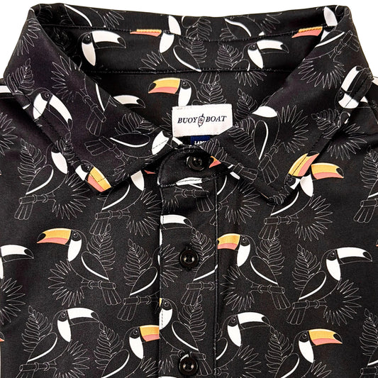 Folded black shirt with toucan pattern on a beige background