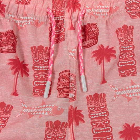 Pink shorts with red tiki and palm tree pattern on a white background