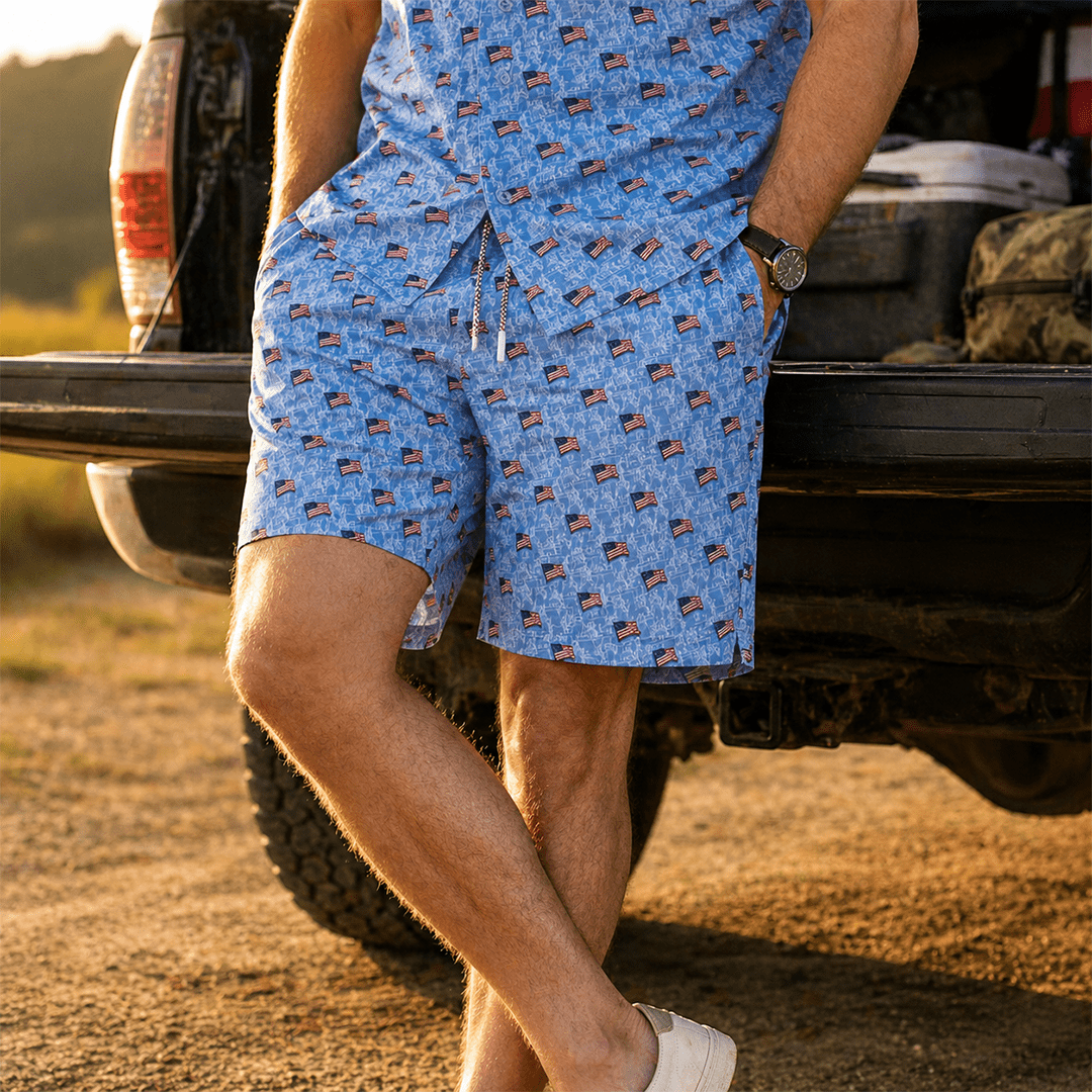 Person wearing blue shorts with American flag pattern standing next to a truck outdoors.