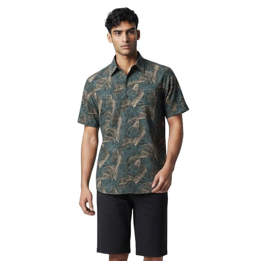 Man wearing a patterned shirt and black shorts on a white background